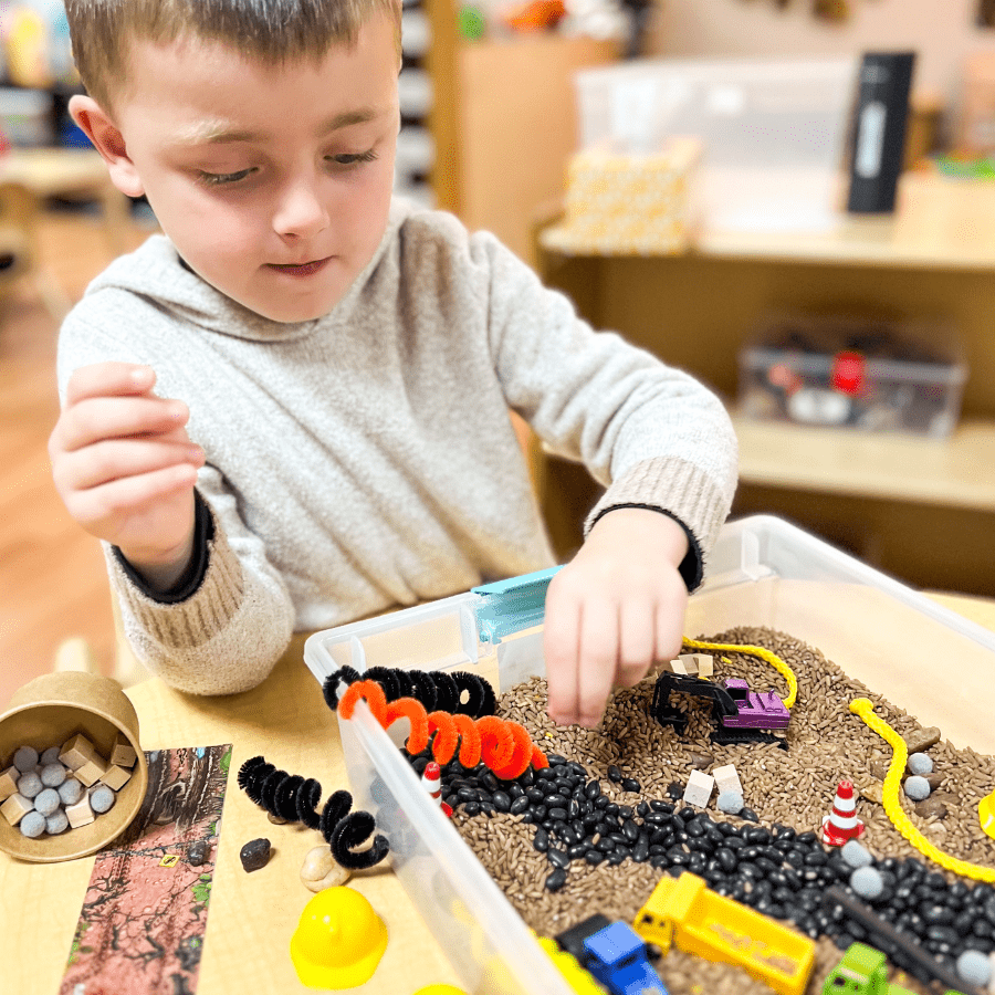 Construction busy bin with sensory materials and toy trucks