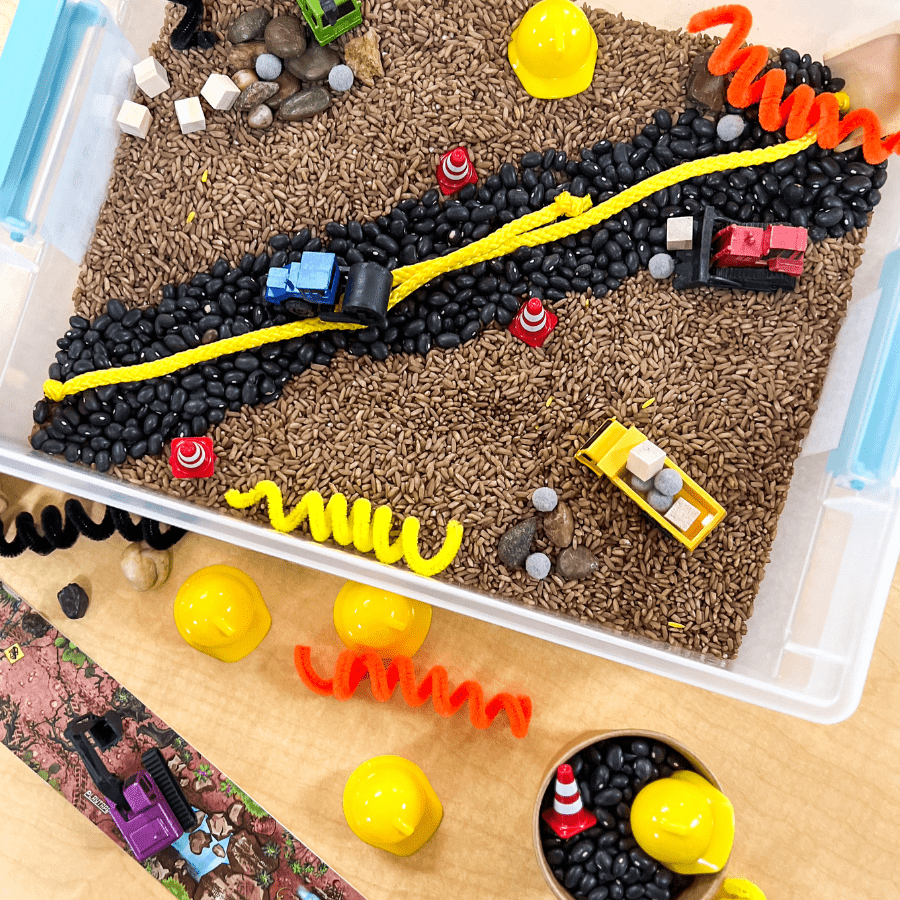 Construction busy bin with sensory materials and toy trucks