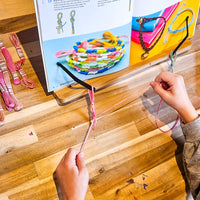 Child using a DIY bracelet craft kit to create handmade jewelry